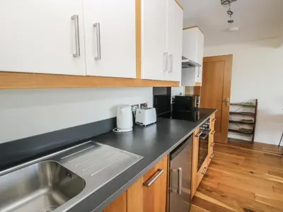 a kitchen with white cabinets and a stainless steel sink at Plum Hill Apartment in Oswestry
