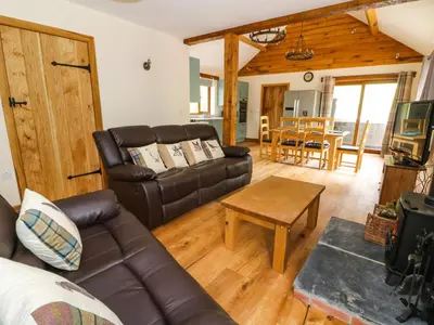 a living room with a leather couch and a table at Ploony Hill Lodge in Bleddfa