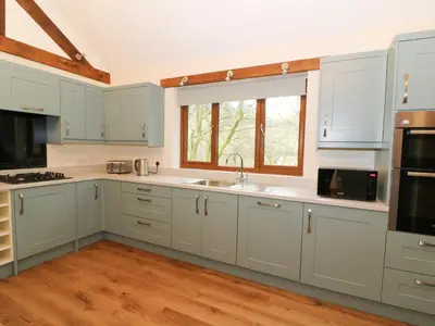 a kitchen with white cabinets and a window at Ploony Hill Lodge in Bleddfa