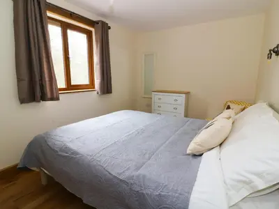 a bedroom with a bed with white sheets and a window at Ploony Hill Lodge in Bleddfa