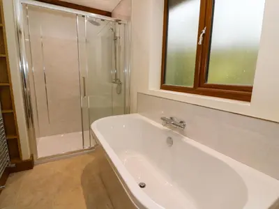 a bathroom with a tub and a glass shower at Ploony Hill Lodge in Bleddfa