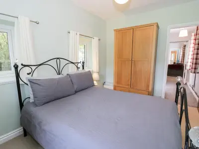 a bedroom with a bed and a wooden cabinet at Dyffryn Bach in Rug