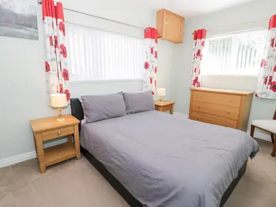 a bedroom with a bed with red and white curtains at Dyffryn Bach in Rug