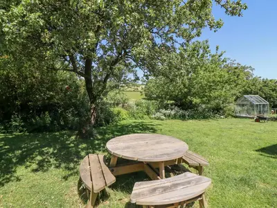 a picnic table and two benches in the grass at Dyffryn Bach in Rug