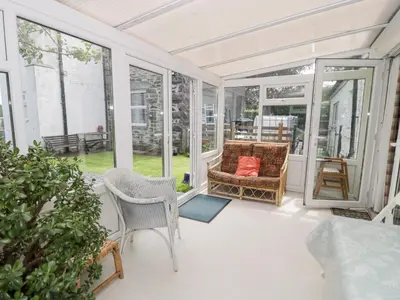 a screened in porch with a couch and chairs at Dyffryn Bach in Rug