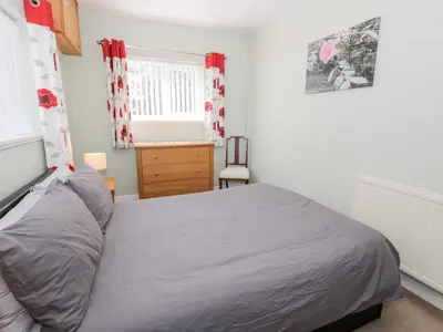 a bedroom with a bed and a dresser and a window at Dyffryn Bach in Rug