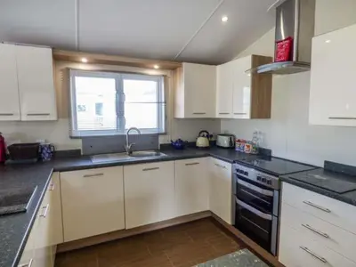 a kitchen with white cabinets and a sink and a window at Clearview Lodge in Borth