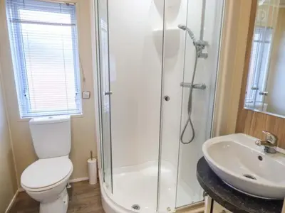 a bathroom with a shower and a toilet and a sink at Clearview Lodge in Borth