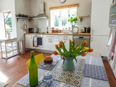 a kitchen with a table with a vase of flowers at Goosepond in Wistanstow