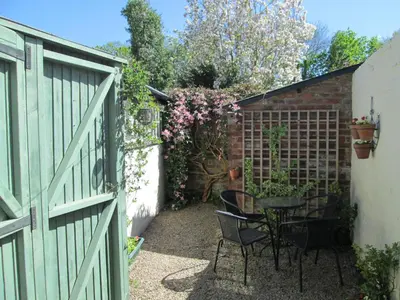 a garden with a table and chairs and a fence at Borrowers Cottage in Condover