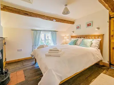 a bedroom with a large bed with towels on it at Borrowers Cottage in Condover