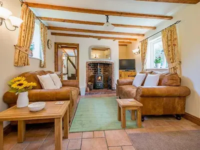 a living room with two couches and a fireplace at Borrowers Cottage in Condover