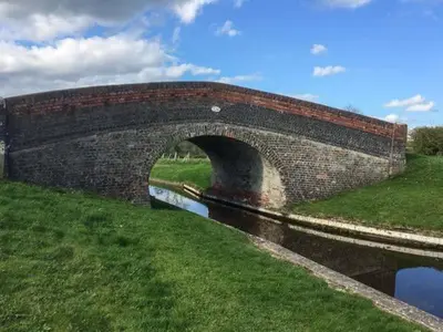 a brick bridge over a river in a field at Gwdihw in Ifton Heath
