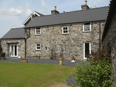 an old stone house with a garden in front of it at Y Bwythyn at Henfaes in Rhydymain