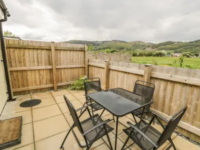 a patio with chairs and a table and a fence at Brickfield Cottage in Machynlleth
