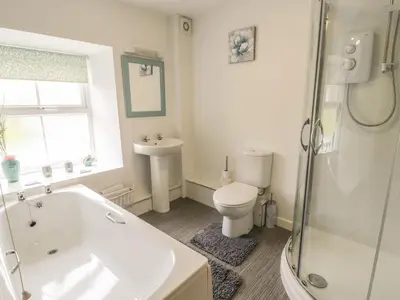 a bathroom with a tub and a toilet and a sink at Brickfield Cottage in Machynlleth