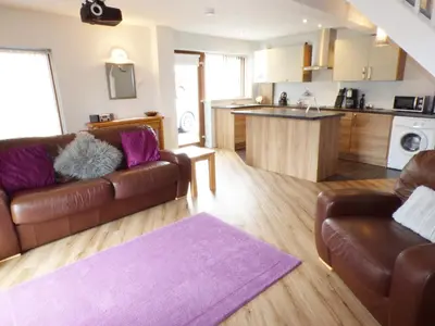 a living room with two brown couches and a kitchen at Penylodge in Builth Wells