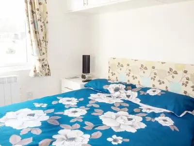 a bed with a blue blanket with white flowers on it at 73-The Lodge in Llanina