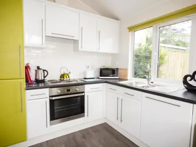 a kitchen with white cabinets and a window at 73-The Lodge in Llanina