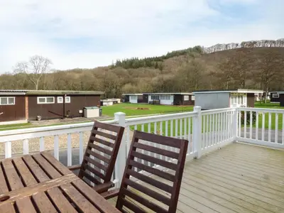 a wooden deck with two chairs on a balcony at 73-The Lodge in Llanina