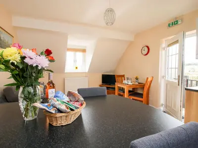 a dining room table with a vase of flowers on it at The Wynnstead Annexe in West Felton