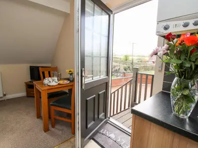 a room with a balcony with a table and a glass door at The Wynnstead Annexe in West Felton