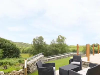 a patio with chairs and a view of a field at Moelfre Cottage in Llanbedr