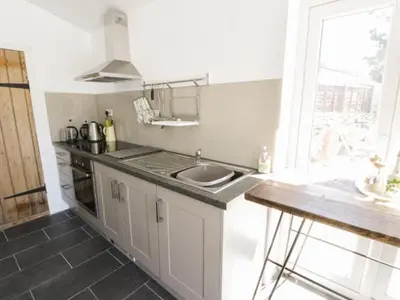 a white kitchen with a sink and a window at 2 Borthwen Cottages in Dyffryn