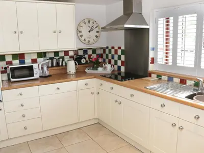 a kitchen with white cabinets and a clock on the wall at Little Beeches in Selattyn