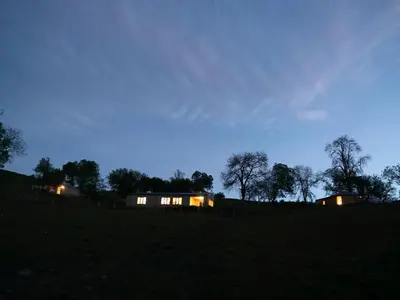 a house with lights on in a field at night at Rolling Hills in Newcastle