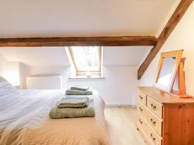 a bedroom with a bed and a dresser and a window at Hen Ysgubor Cottage in Bala