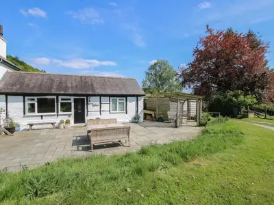 a white cottage with a patio and a gazebo at The Old Beams at Pont y Forwyn in Llansantffraid-ym-Mechain