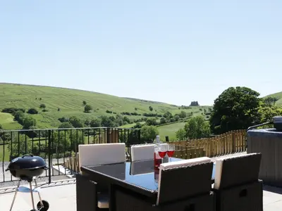 a table and chairs on a balcony with a view at 1 Beacon View Barn in Felindre