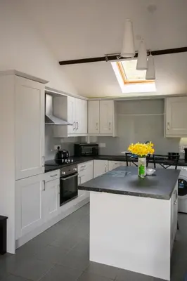 a kitchen with white cabinets and a counter with flowers on it at 1 Beacon View Barn in Felindre