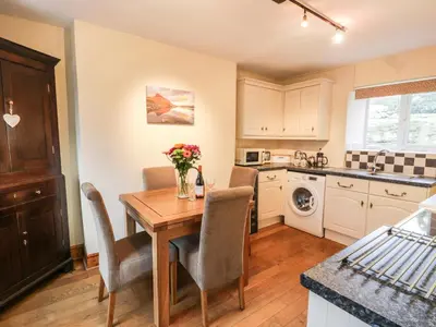 a kitchen with a wooden table and chairs and a sink at Llwyn Celyn in Llanfachreth