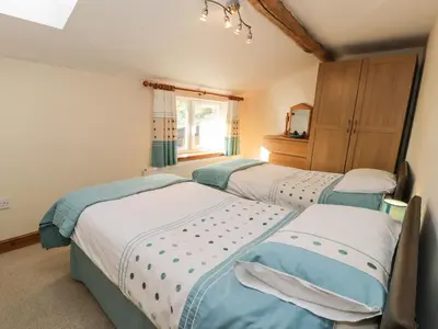 a bedroom with three beds and a window at Yr Hen Dy in Ffestiniog
