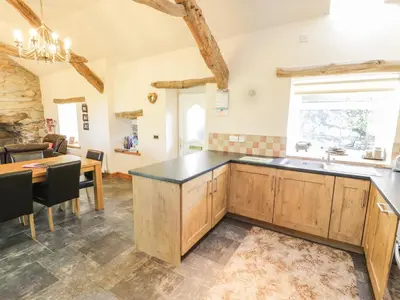 a kitchen with wooden cabinets and a table and a dining room at Yr Hen Dy in Ffestiniog