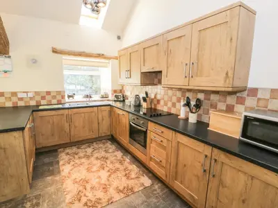 a kitchen with wooden cabinets and a black counter top at Yr Hen Dy in Ffestiniog