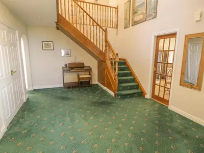 an empty hallway with a staircase and a piano at Awel Y Llan in Llanfair