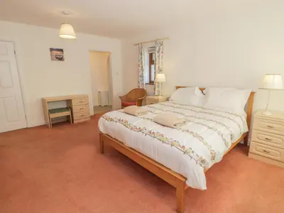 a bedroom with a large bed and a desk at Awel Y Llan in Llanfair