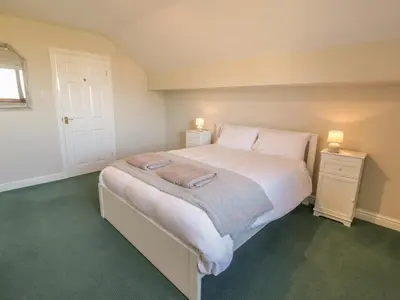 a bedroom with a large bed with white sheets and pillows at Awel Y Llan in Llanfair