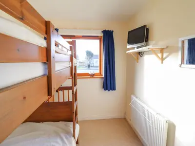 a bedroom with a bunk bed and a television at Dehangfa in Fairbourne