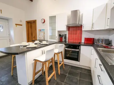a kitchen with white cabinets and a black counter top at Cornel Glyd in Dyffryn