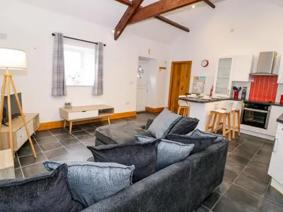 a living room with a couch and a kitchen at Cornel Glyd in Dyffryn