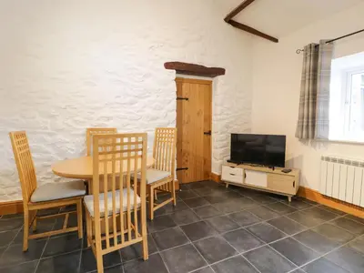 a dining room with a table and chairs and a tv at Sisial-y-Mor in Dyffryn