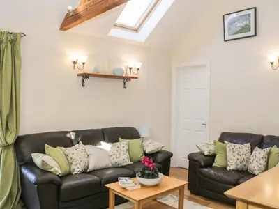 a living room with a black leather couch and a table at Clun Forest Cottage in Monkhopton