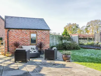 a patio with two chairs and a brick house at Clun Forest Cottage in Monkhopton