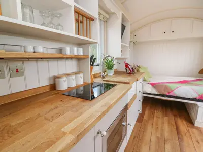 a kitchen with white cabinets and wooden floors at Shepherd's View in Saint Harmon