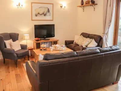 a living room with a leather couch and a tv at Ryelands Cottage in Easthope