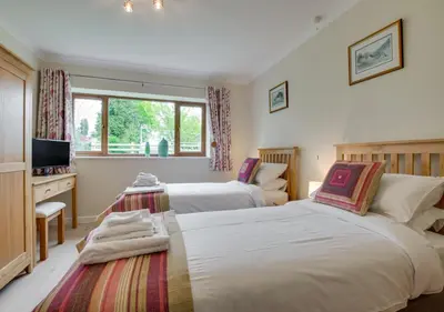 a bedroom with two beds and a desk and a television at Bwthyn Bryn yr Aber in Bala